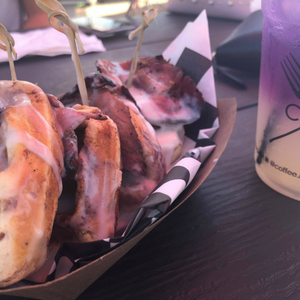 Cinnamon rolls and bacon in a dish, with lavender lemonade on a table. 